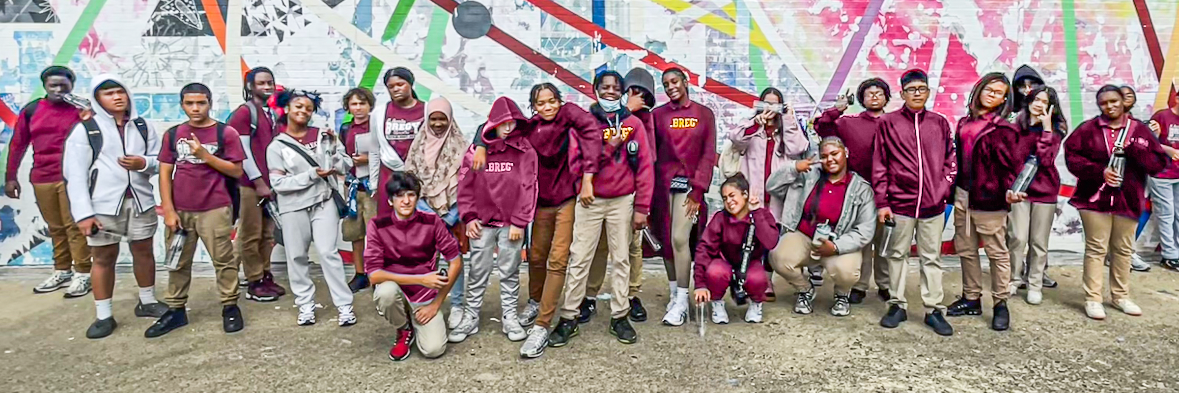 A large group of middle school students from Bregy Elementary School pose together in front of a colorful outdoor mural.
