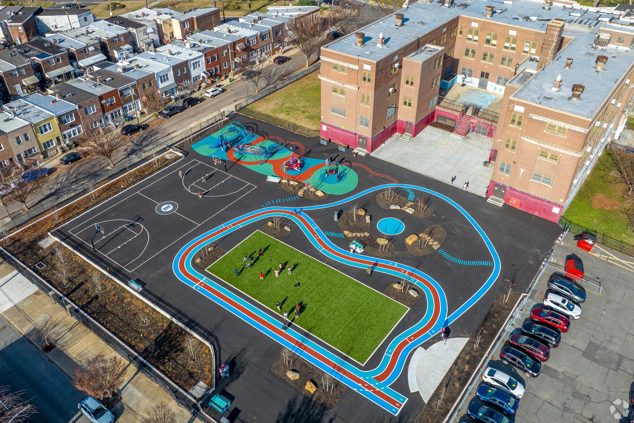verhead view of F. Amedee Bregy Elementary School's colorful outdoor play area featuring a running track, basketball court, turf field, and playground structures