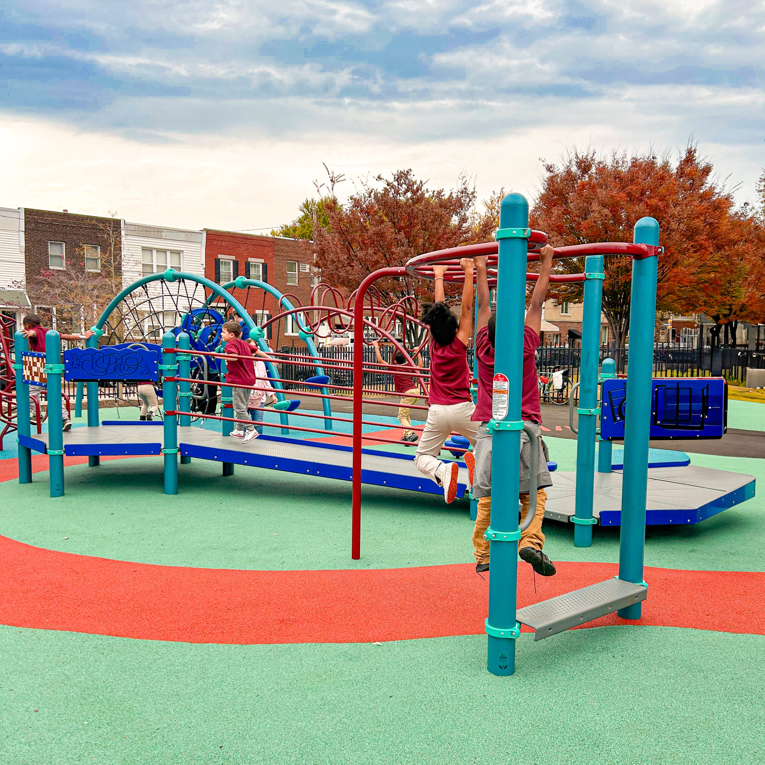 Children play on a multicolored jungle gym and monkey bars on soft green and red rubber surfacing at Bregy Elementary School