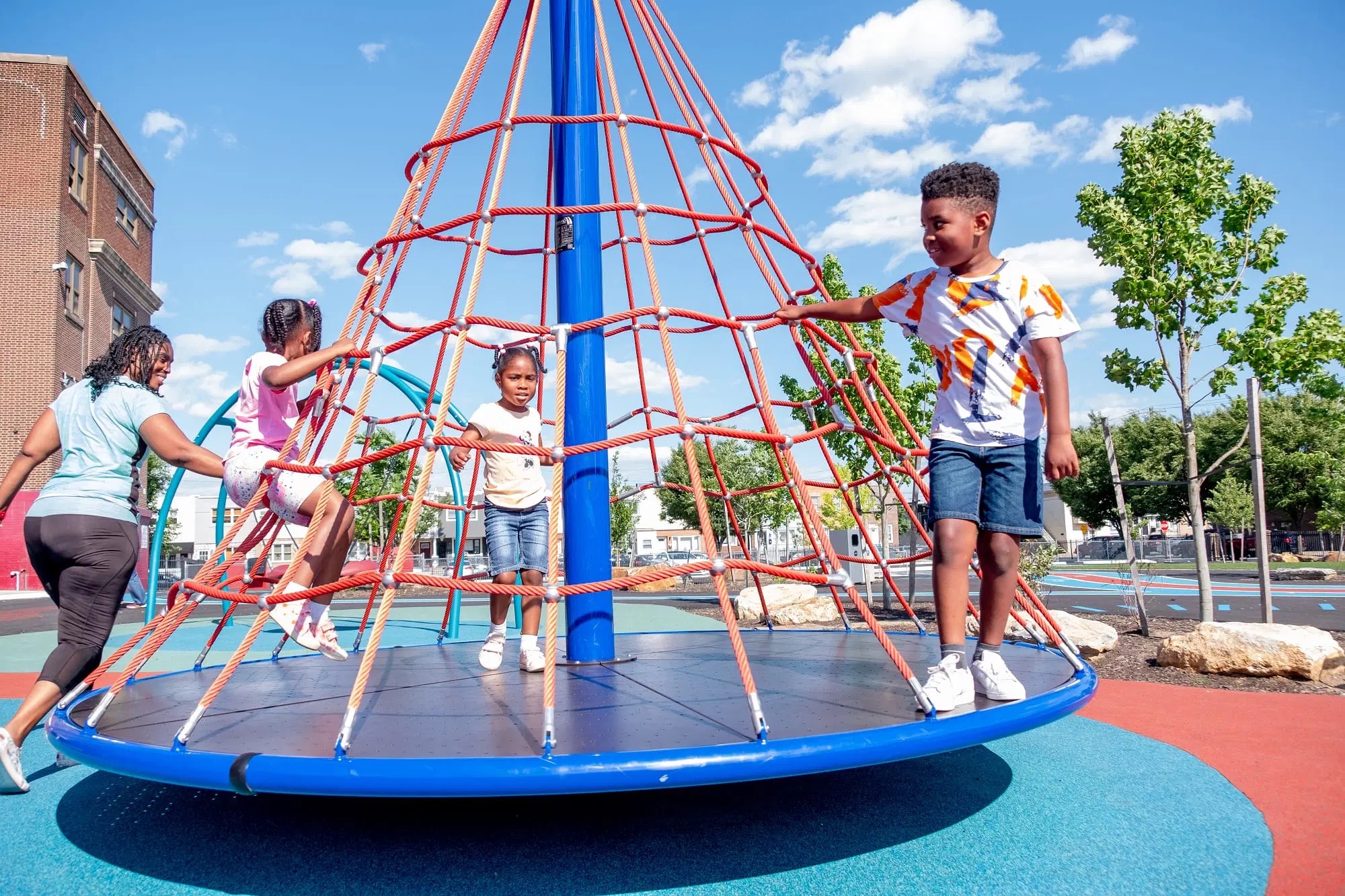 Children climb and spin on a red and blue rope play structure at Bregy Elementary School’s outdoor playground